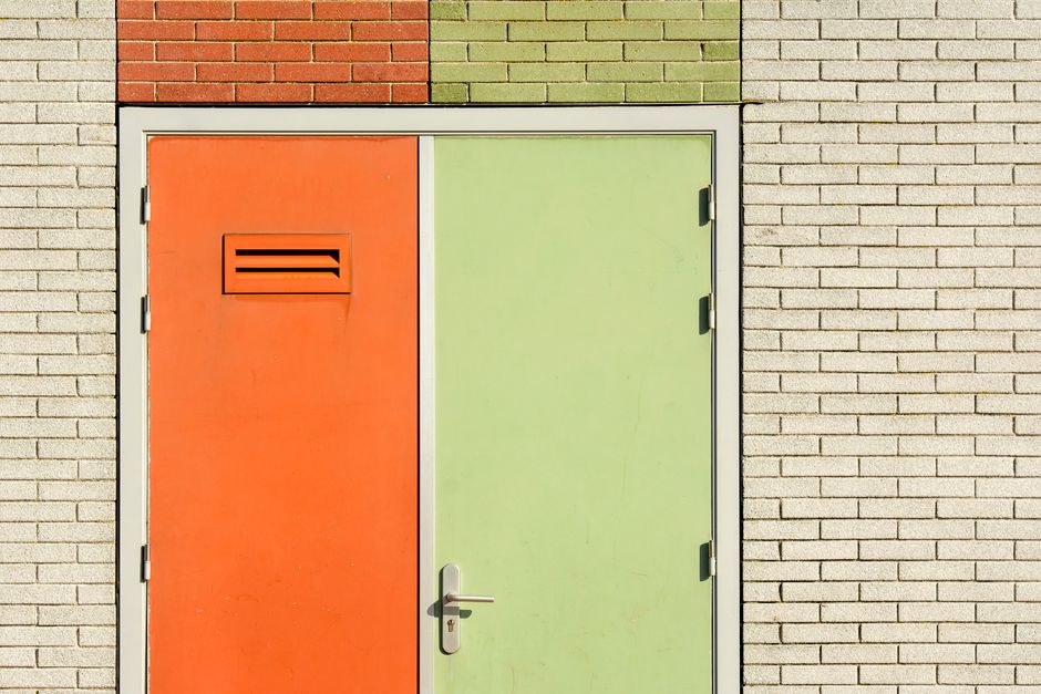 Orange and green door on a brick wall with modern design and security features. Photo by Jan van der Wolf on Pexels