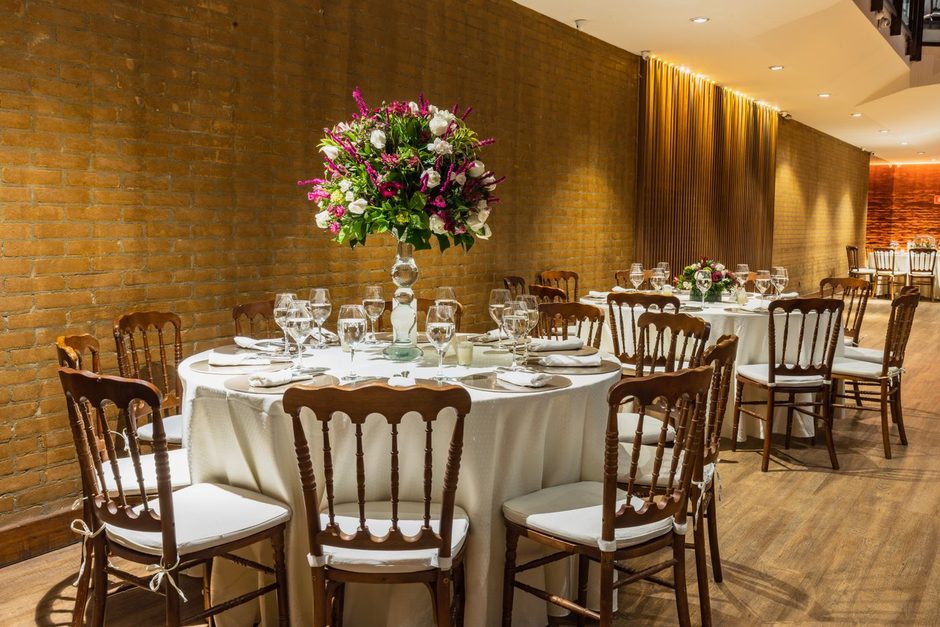 Event venue set with round banquet tables and flower centerpieces. Photo by Matheus Bertelli on Pexels