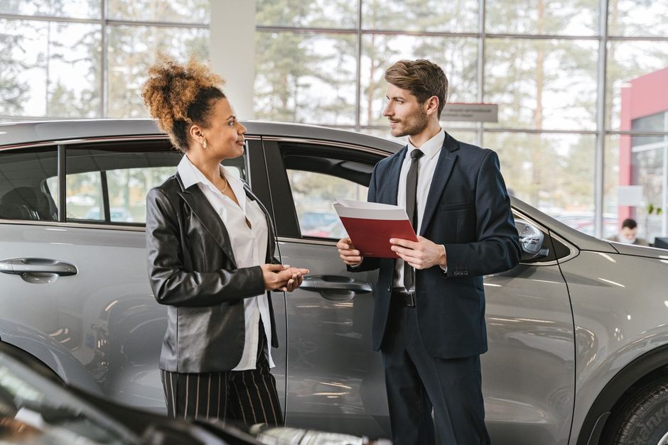 Car salesman showing a vehicle to a customer in a bright showroom. Photo by Antoni Shkraba on Pexels