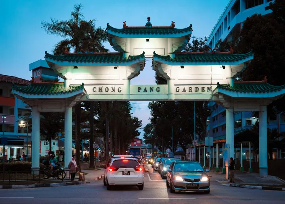 Photo by Calvin Seng on Pexels Chong Pang Garden entrance gate illuminated at dusk with traffic and pedestrians in Singapore.