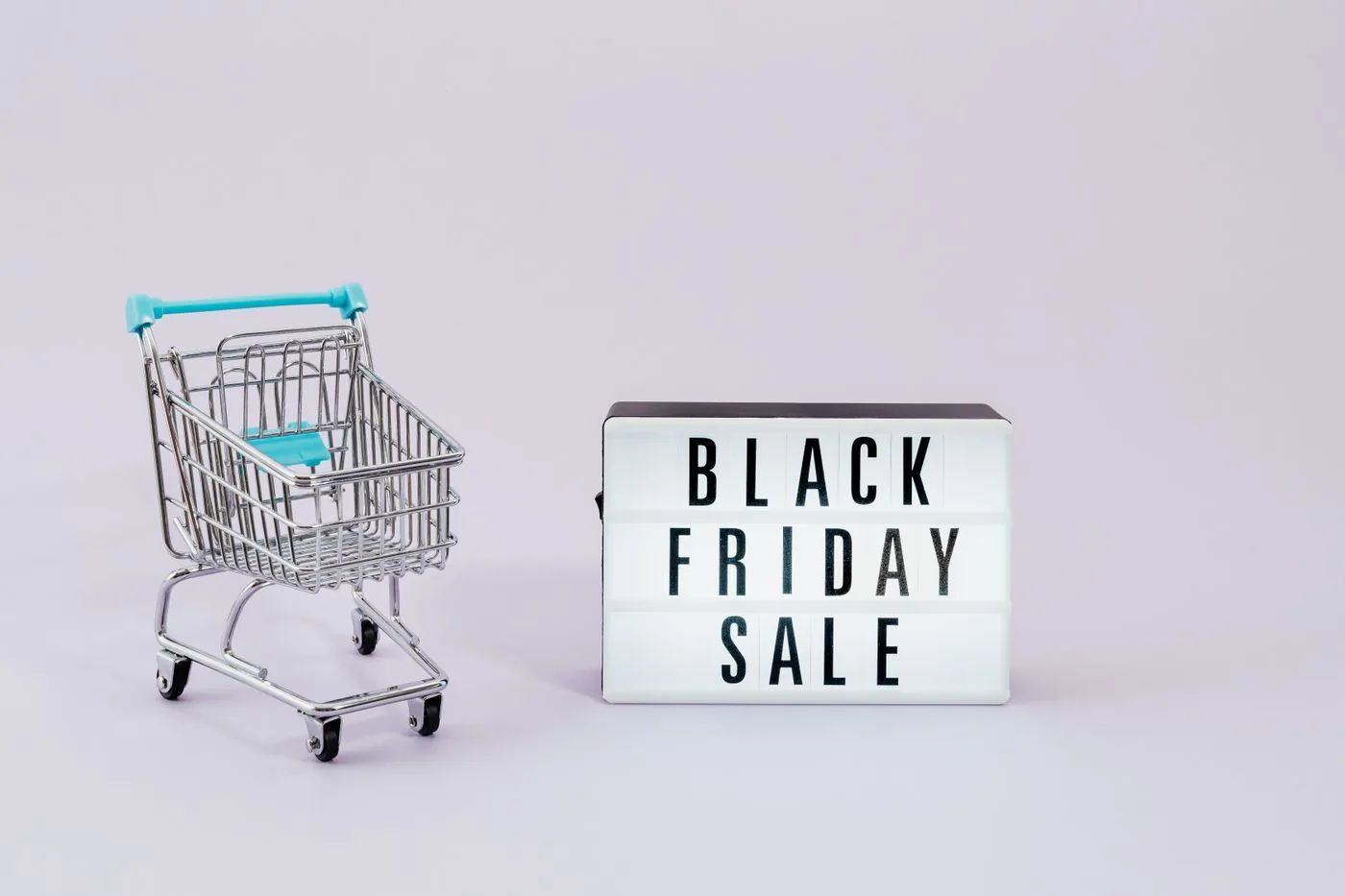 Shopping cart beside a Black Friday sale sign for campaign growth. Photo by www.kaboompics.com on Pexels