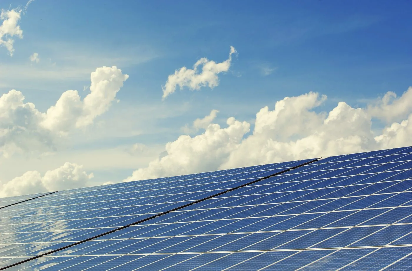 EV Charger Installation — Solar panel array under a bright blue sky with clouds
