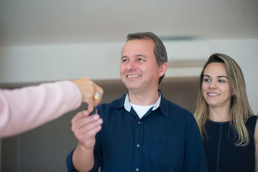 Real estate agent handing over house keys to a smiling homeowner. Photo by Kampus Production on Pexels