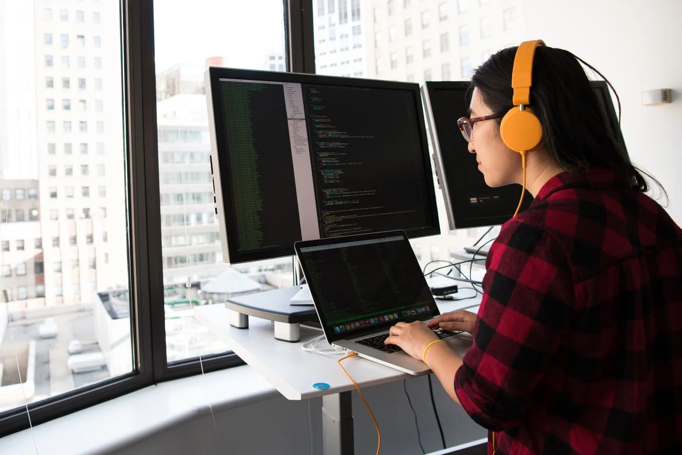Software developer working on product code with multiple monitors. Photo by Christina Morillo on Pexels