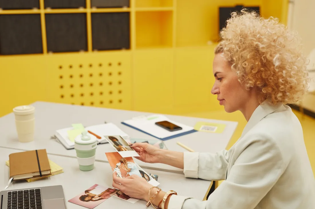Business owner reviewing printed brochure copy at a desk in a bright office. Photo by Moe Magners on Pexels