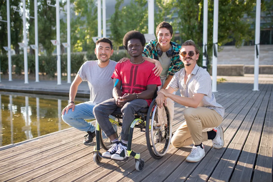 Group of friends relaxing outdoors with a man using a wheelchair on a sunny deck in Australia. Photo by Kampus Production on Pexels