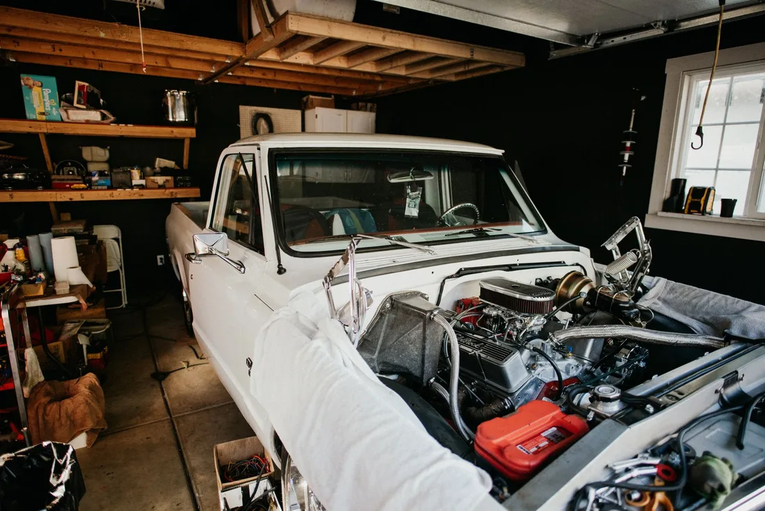 A vintage pickup truck undergoing engine repairs in a well-equipped home garage. Photo by dumitru B on Pexels