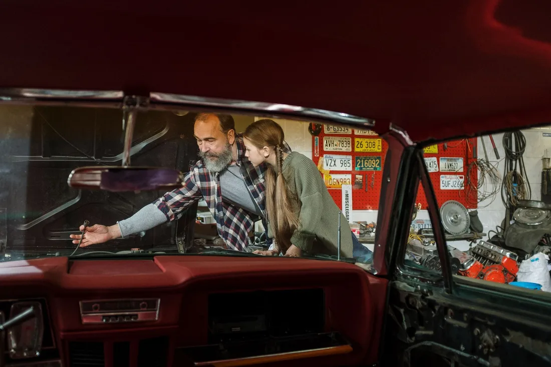 Two customers lean in to look at an engine with a mechanic in a garage. Photo by cottonbro studio on Pexels