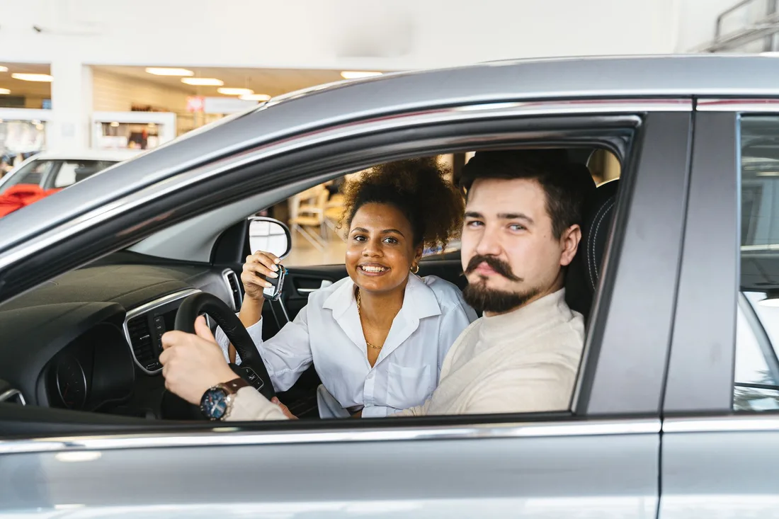 Smiling couple sitting in a silver car at a repair shop after service. Photo by Antoni Shkraba on Pexels