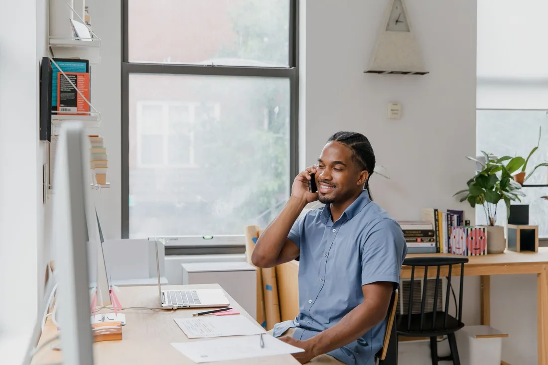 Smiling business owner taking a customer inquiry call at a desk. Photo by RDNE Stock project on Pexels