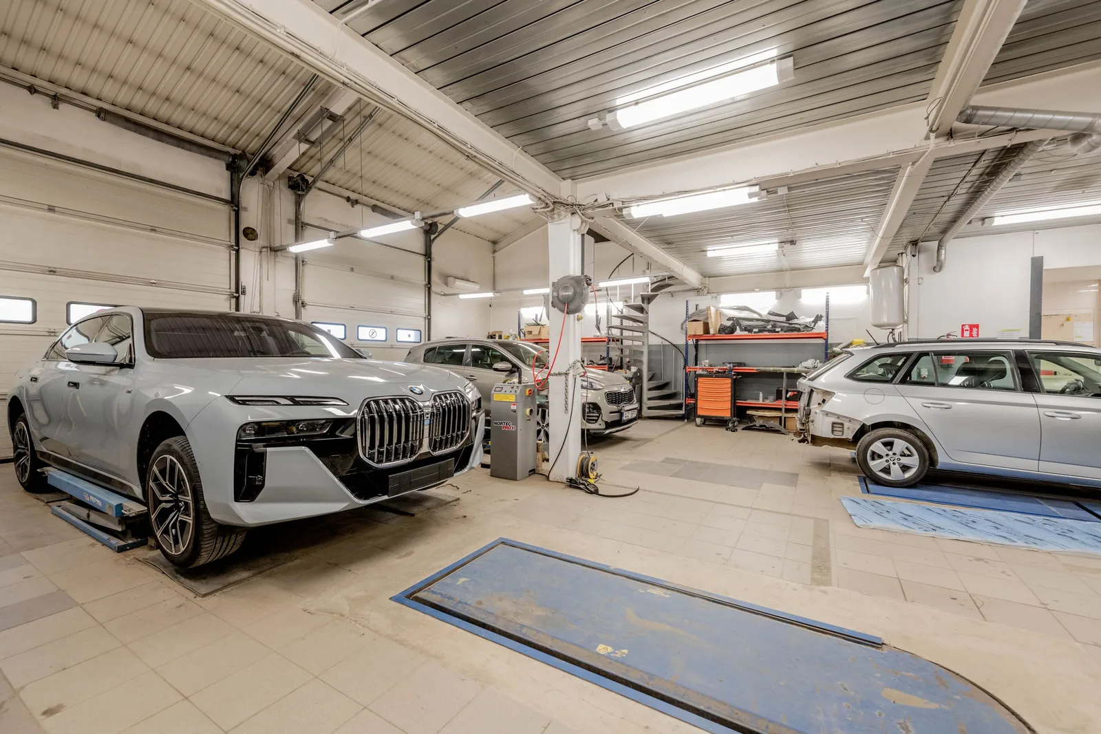 Spacious indoor car garage featuring luxury vehicles under maintenance, showcasing an organized and professional workspace. Photo by Renee Razumov on Pexels