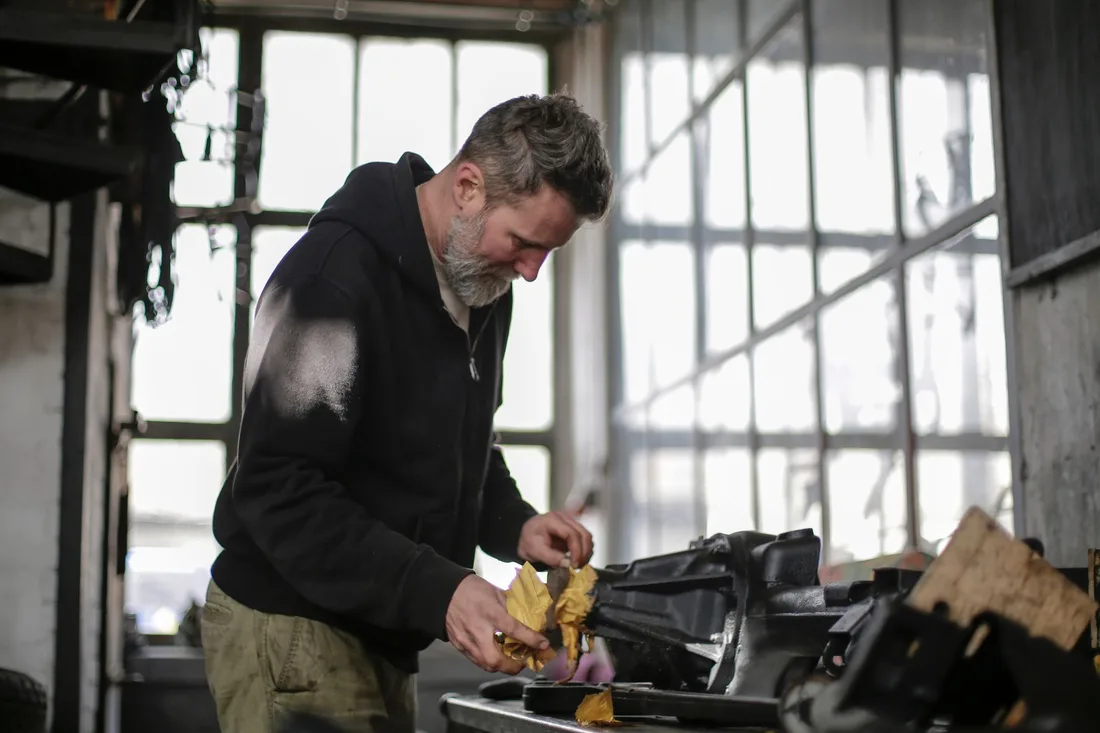 Side view of middle aged man in hoodie standing near workbench and cleaning instruments with rag while working in workshop. Photo by Andrea Piacquadio on Pexels