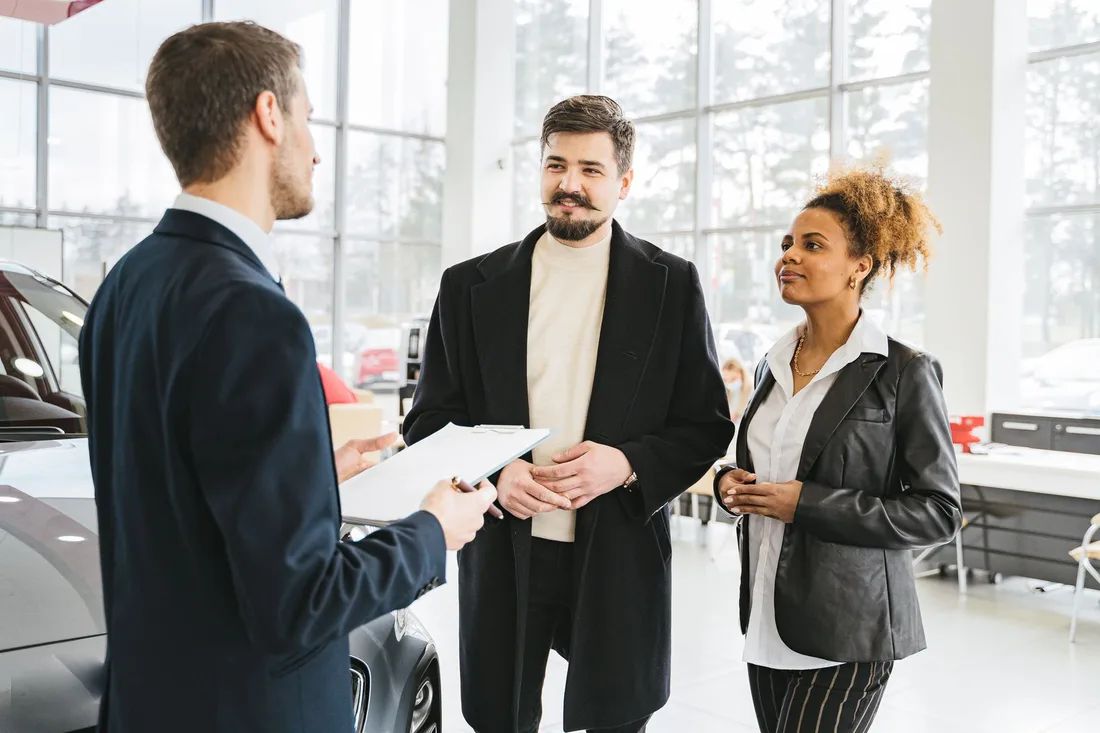 Happy couple discussing car purchase with dealer in showroom. Professional interaction and consultation. Photo by AI25.Studio  Studio on Pexels