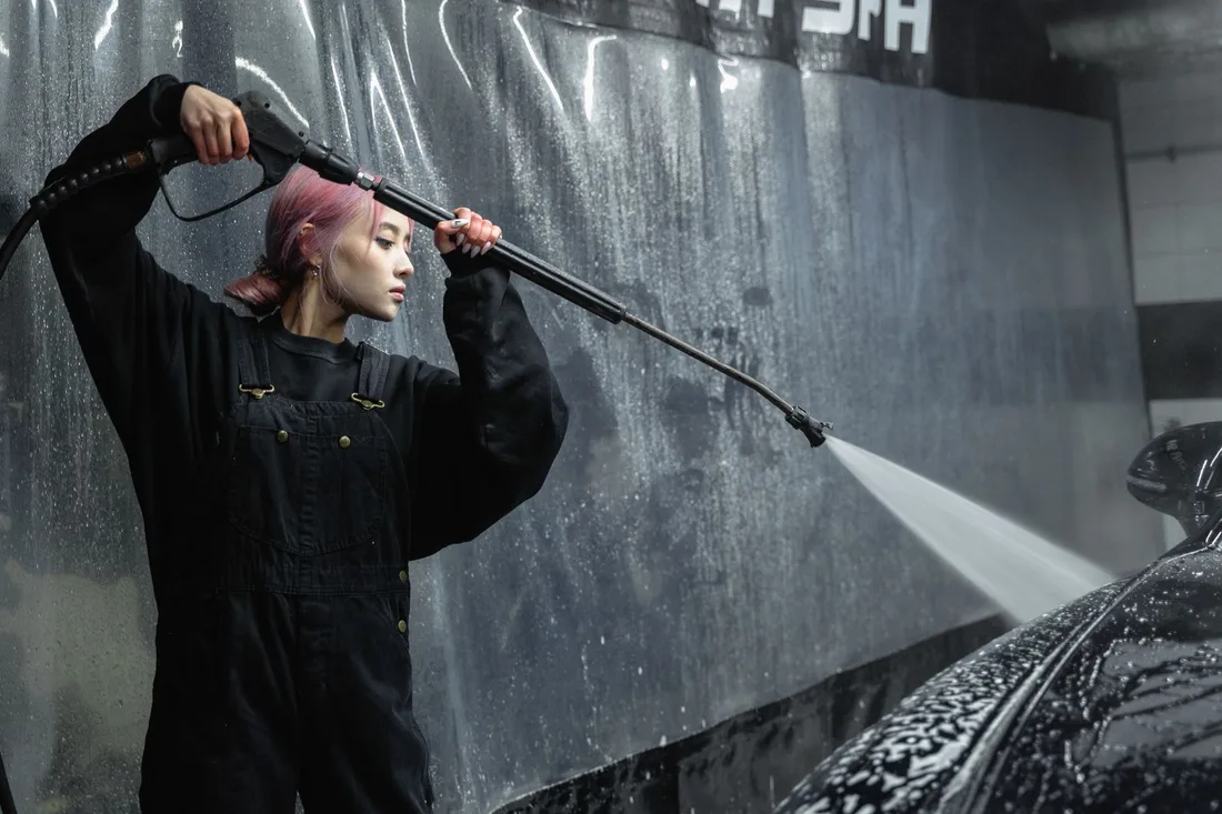 A woman using a pressure hose for car cleaning in an indoor garage. Photo by Tima Miroshnichenko on Pexels