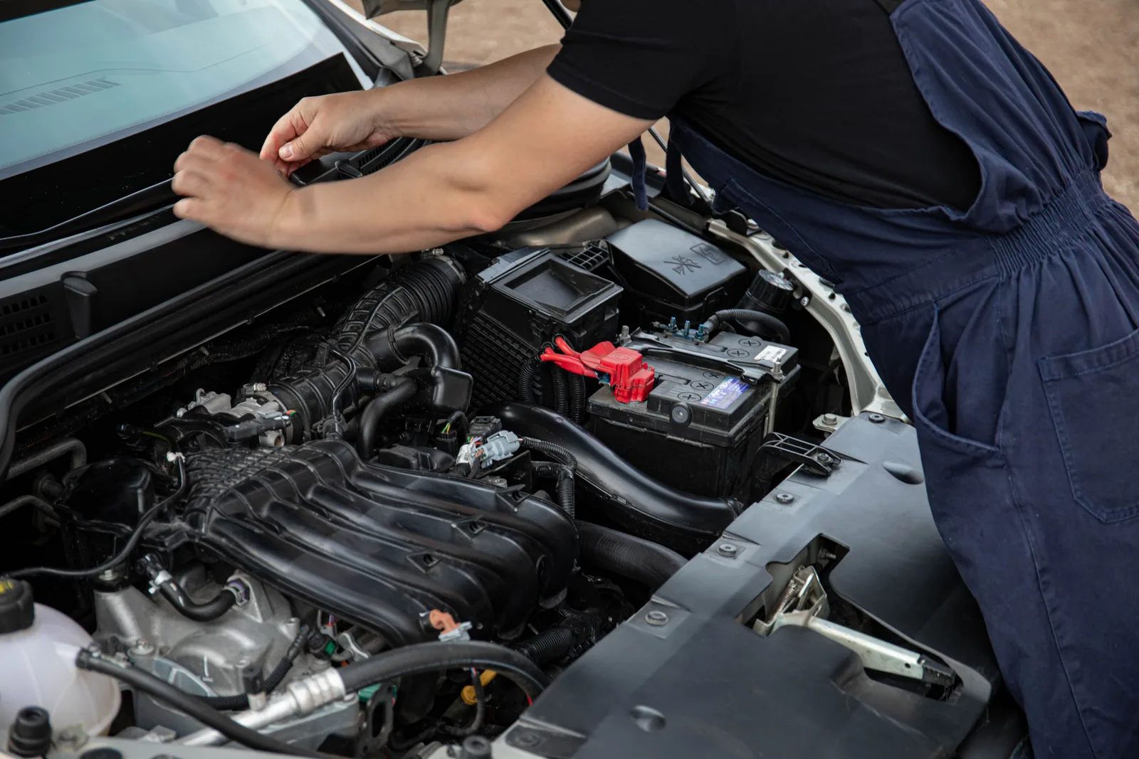 Mechanic performing maintenance on a car engine outdoors during the day. Photo by Sergey  Meshkov on Pexels