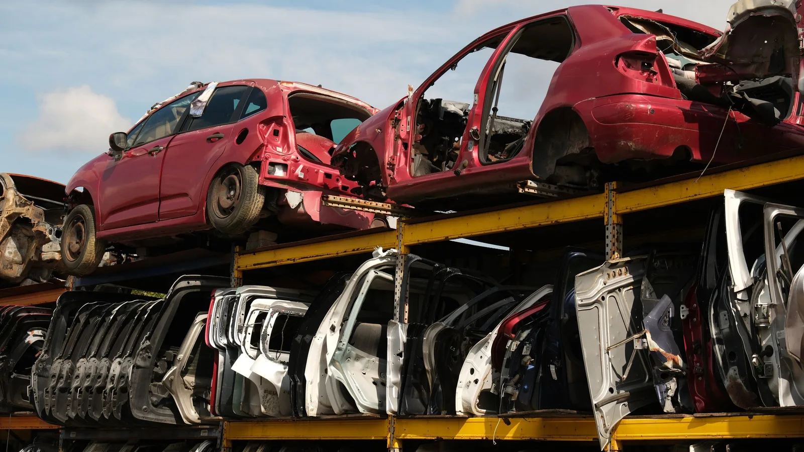 Salvage yard rack stacked with used car doors and wrecked cars on top. Photo by Aziz Er on Pexels