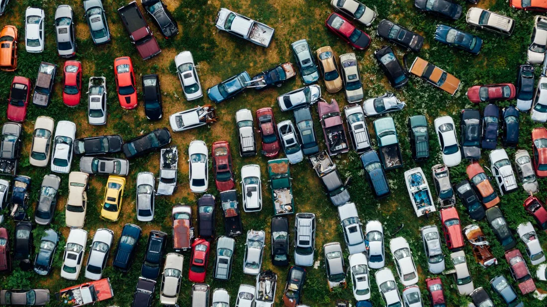 A top-down view of vibrant, abandoned cars in a scrapyard, showcasing urban decay. Photo by K on Pexels