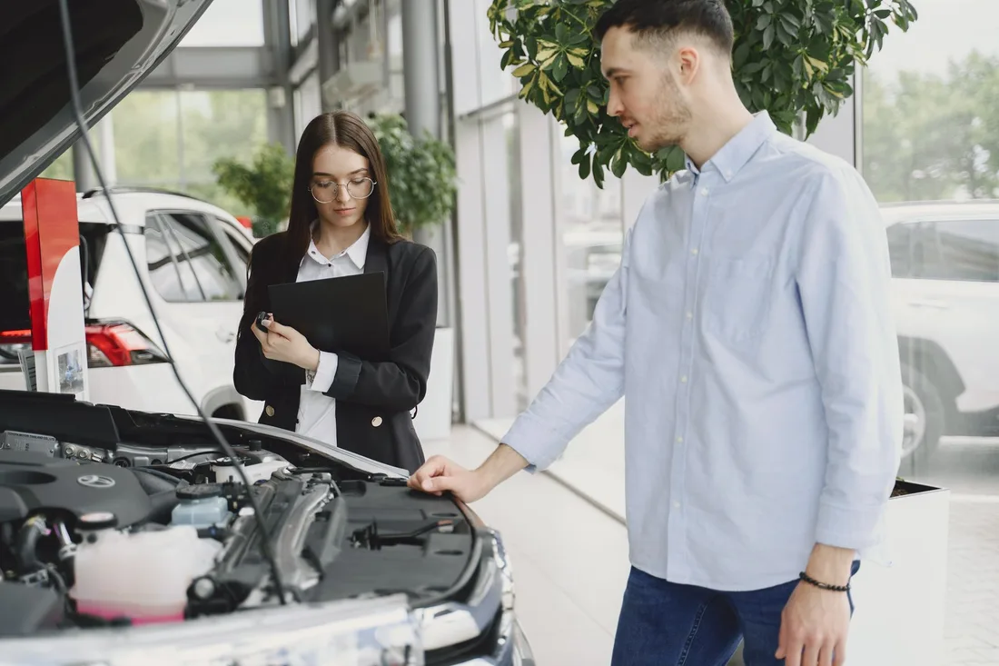 Service advisor and customer looking under the open hood of a car. Photo by Gustavo Fring on Pexels