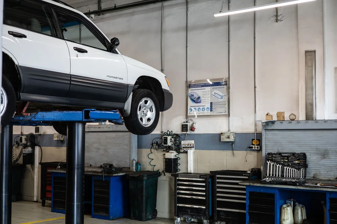 A car is elevated on a lift in a modern automotive repair shop, showcasing tools and equipment. Photo by Artem Podrez on Pexels