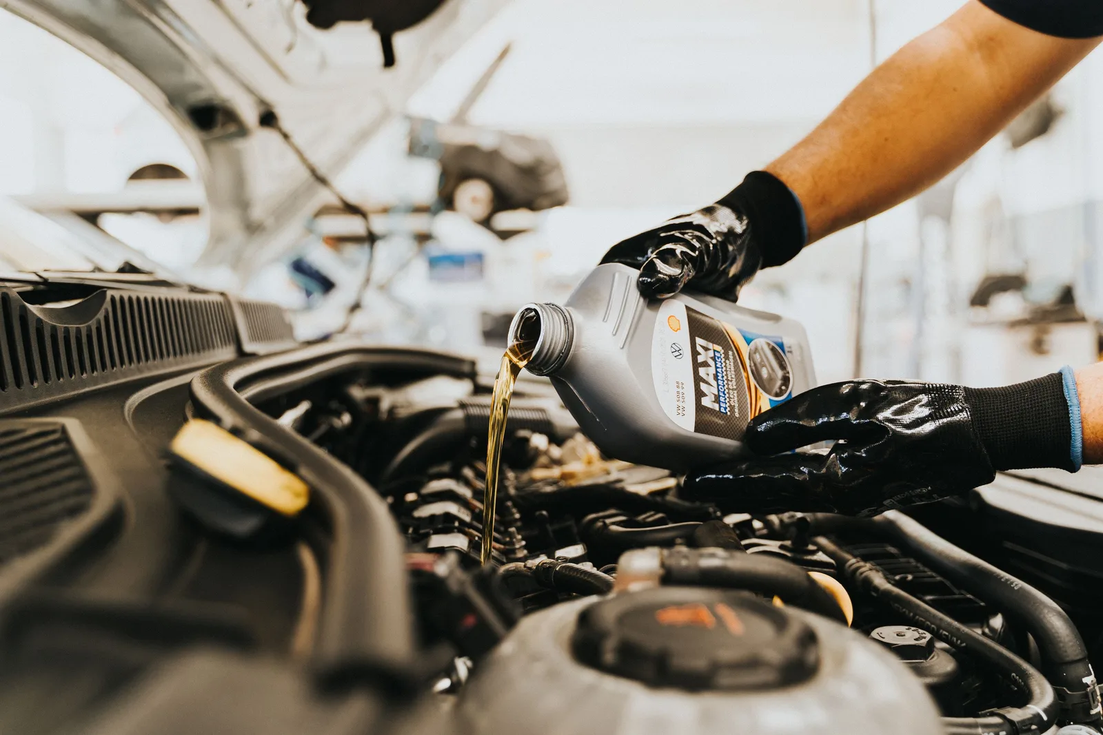 Close-up of a mechanic pouring engine oil into a car engine in an auto repair shop. Photo by Daniel Andraski on Pexels