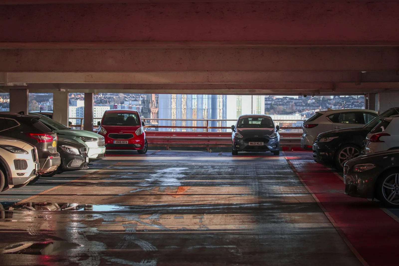 Covered parking garage with rows of parked cars and open driving lane. Photo by Boys in Bristol Photography on Pexels