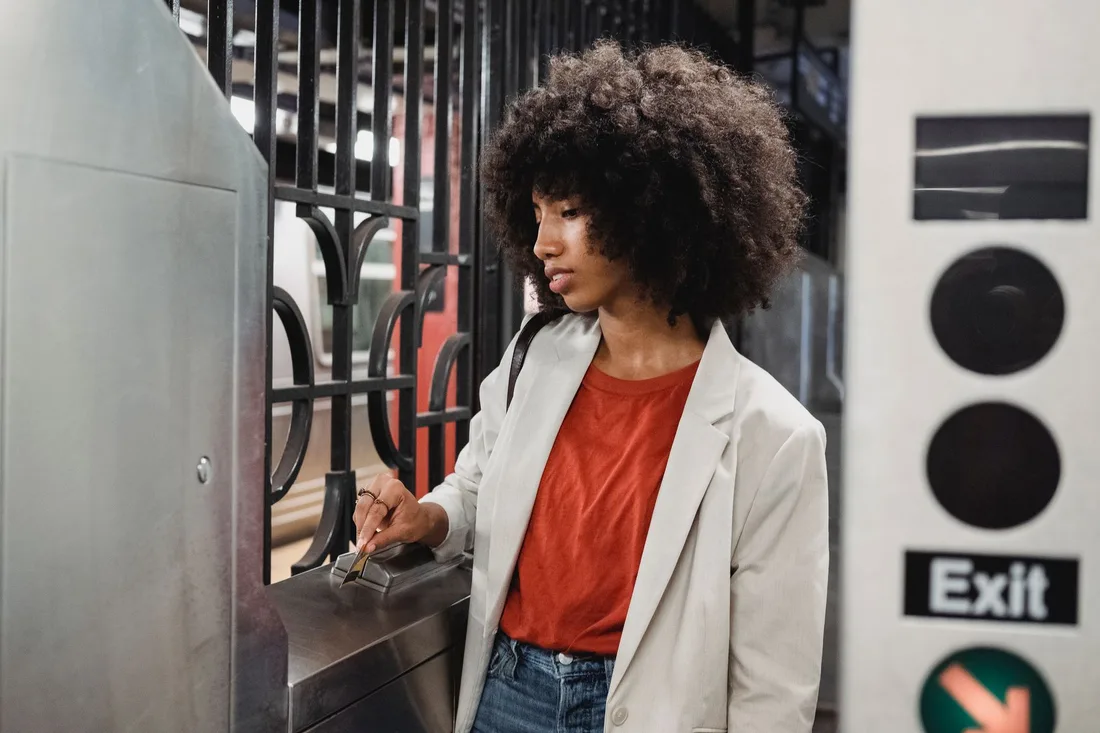 Woman holding a ticket at a parking garage exit gate and ticket machine. Photo by Roberto Hund on Pexels