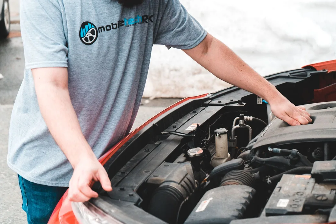 Helper connecting jump leads to a stalled car battery at the roadside. Photo by Erik Mclean on Pexels
