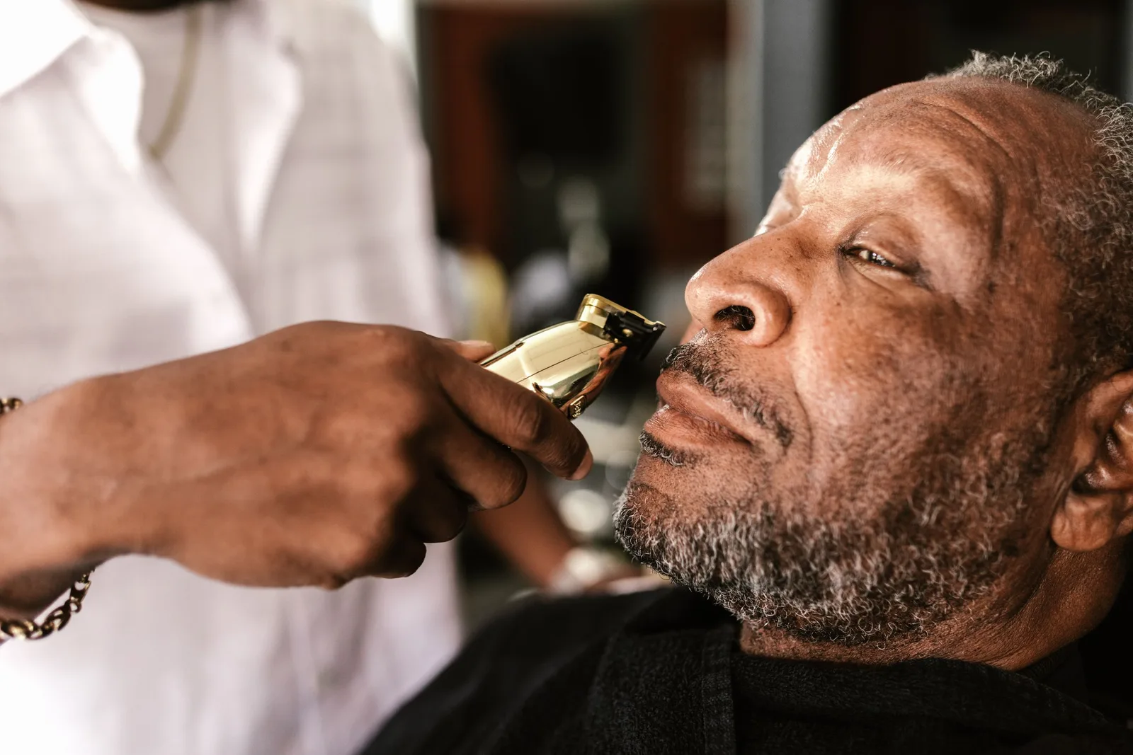 An African American man getting a beard trim at a barber shop, focusing on facial hair grooming. Photo by RDNE Stock project on Pexels