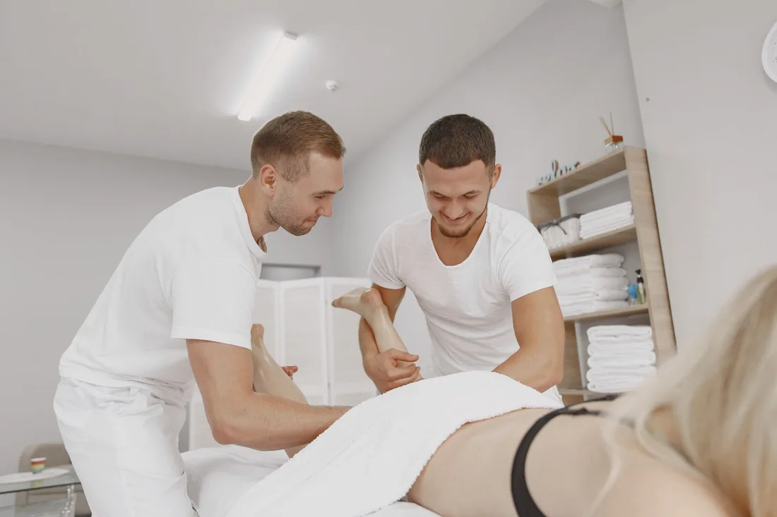 Two male masseurs perform a massage therapy on a client in a spa setting. Photo by Gustavo Fring on Pexels