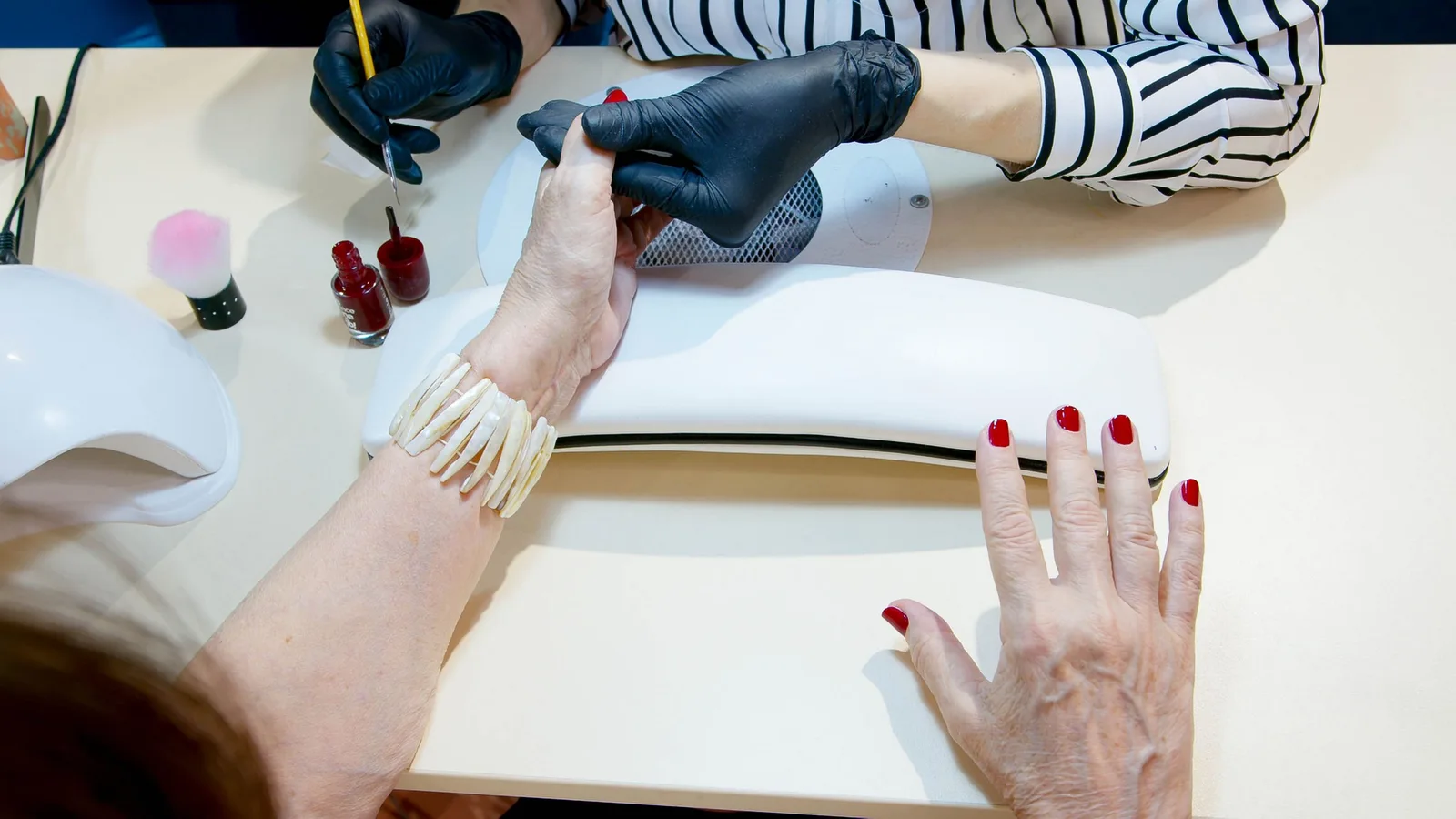Top view of a professional manicure session with red nail polish application in a modern salon. Photo by Artem Podrez on Pexels