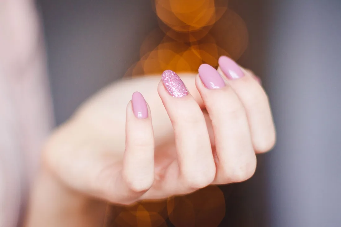 Hand with neat soft pink manicured nails against a warm blurred background. Photo by Valeria Boltneva on Pexels