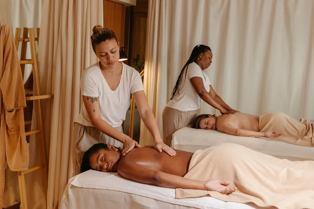 Women receiving soothing massages in a cozy spa for relaxation and stress relief. Photo by Jonathan Borba on Pexels