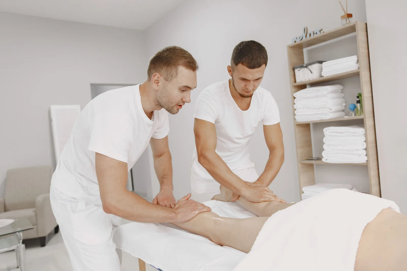 Two male therapists providing leg massage in a tranquil spa environment. Photo by Gustavo Fring on Pexels