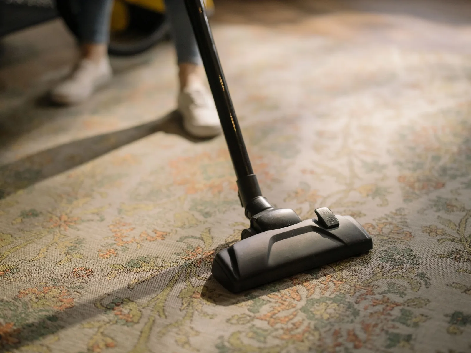 Vacuum cleaner head cleaning a patterned rug on a floor. Photo by cottonbro studio on Pexels