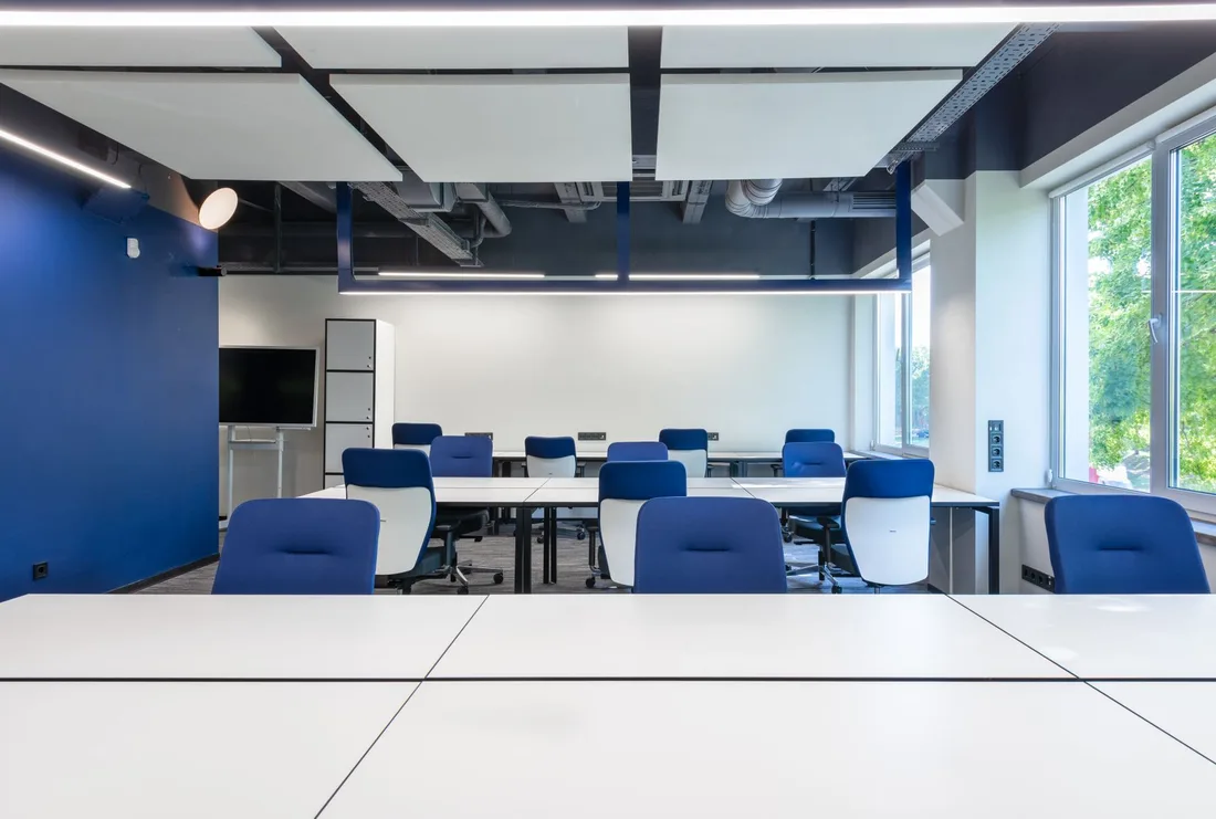 Spotless open plan office with white desks and blue chairs in bright light. Photo by Max Vakhtbovych on Pexels
