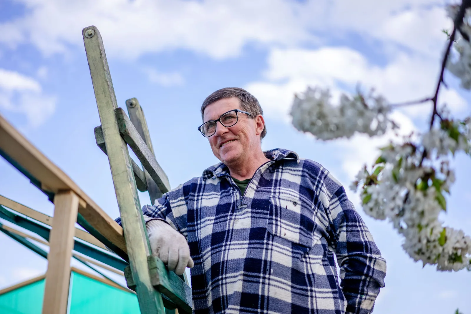 Smiling homeowner on a ladder beside a house roofline. Photo by Atlantic Ambience on Pexels