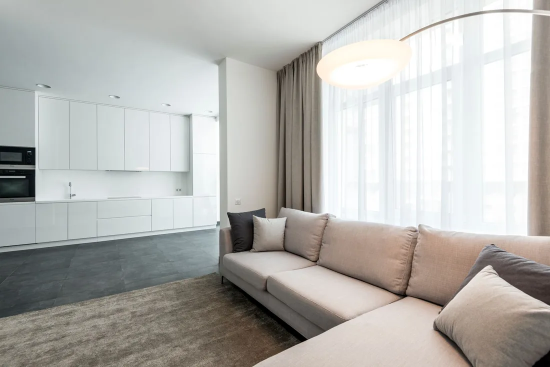 Bright tidy living room with a light sectional sofa and large windows. Photo by Max Vakhtbovych on Pexels