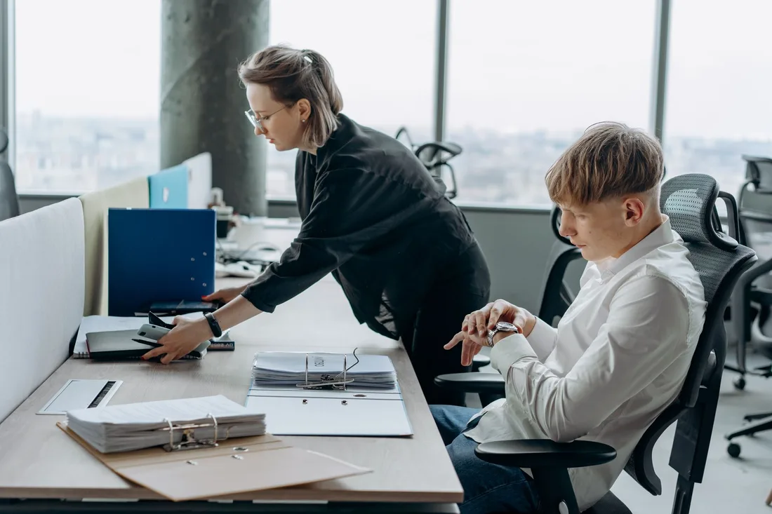 Office workers at their desks in a bright open office. Photo by Mikhail Nilov on Pexels