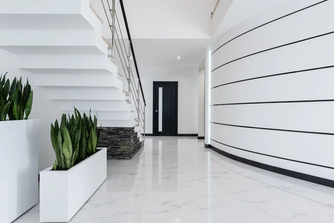 Bright white apartment building lobby with stairs and indoor plants. Photo by Max Vakhtbovych on Pexels