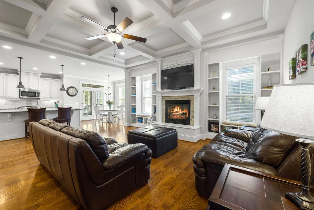 Warm open plan living room with leather sofas, fireplace and ceiling fan. Photo by Curtis Adams on Pexels