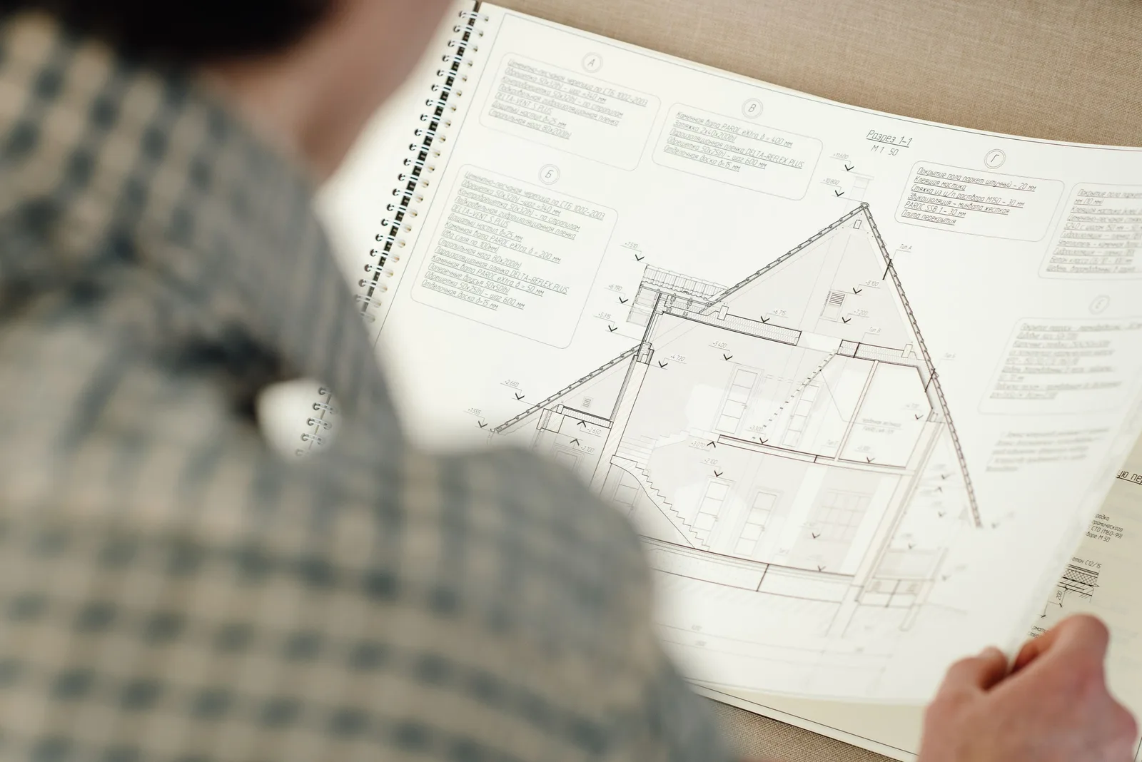 Person reviewing house plans and drawings on paper. Photo by Ivan S on Pexels