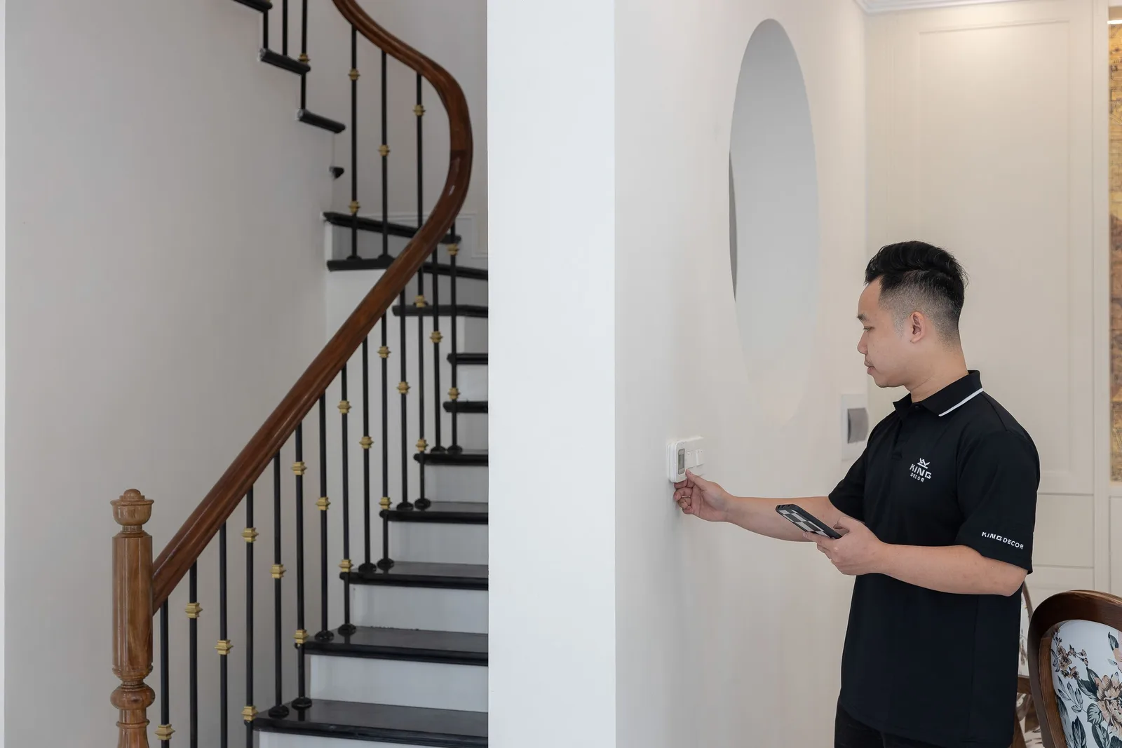 Installer holding a tablet next to a smart wall switch inside a home. Photo by HONG SON on Pexels