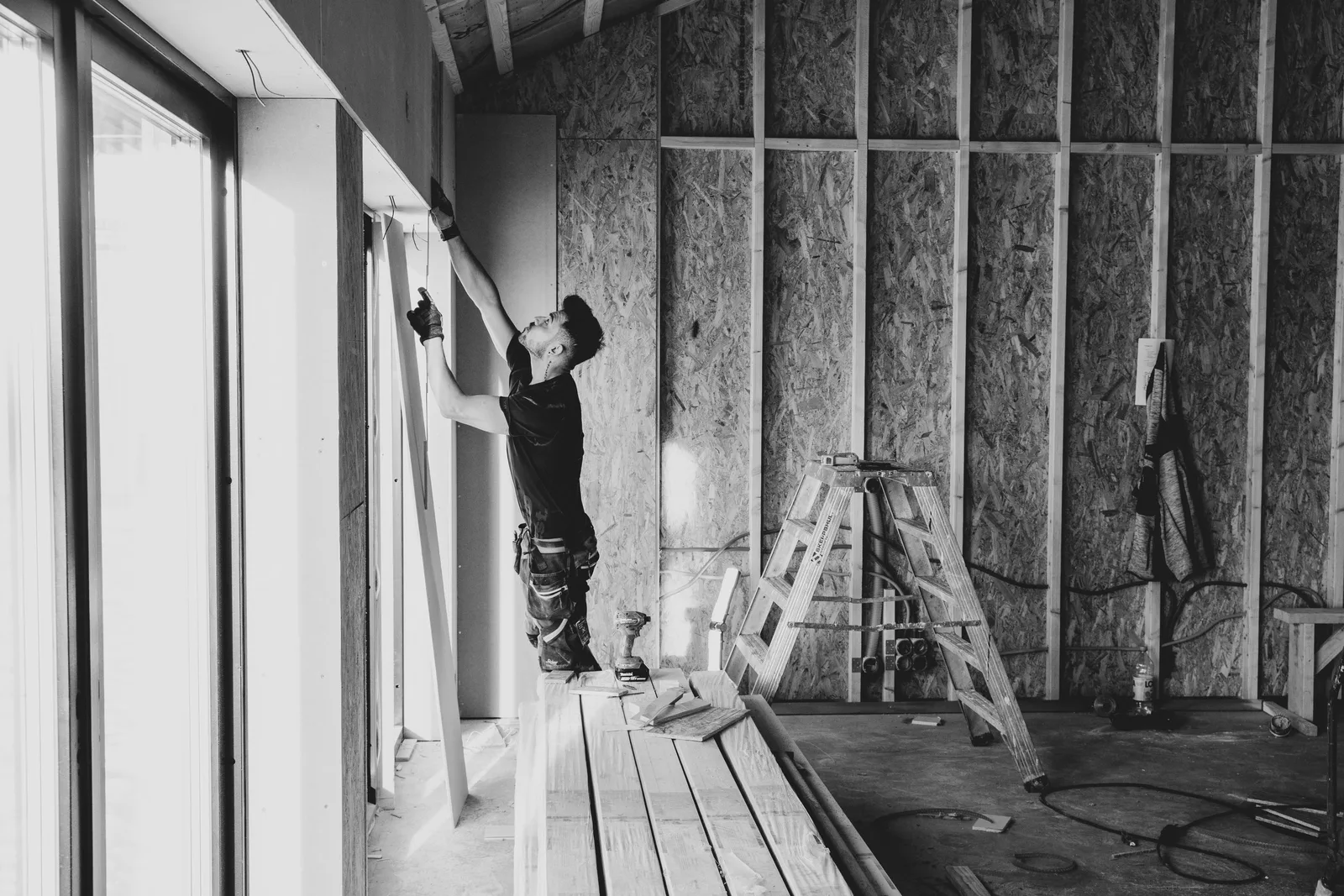 Worker fitting insulation batts between wall studs inside a building. Photo by Jimmy Nilsson Masth on Pexels