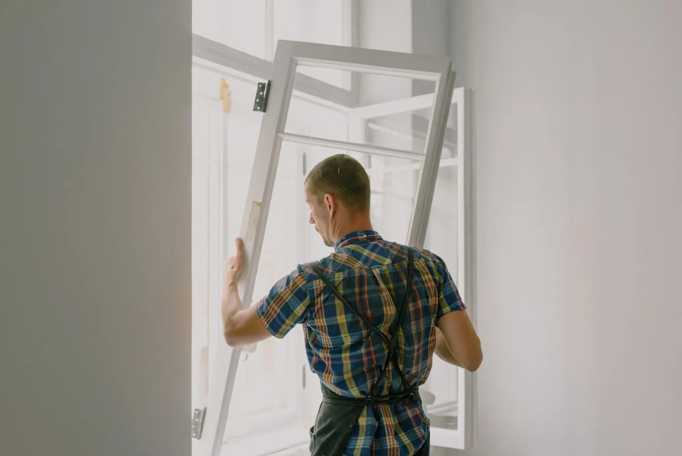 Installer fitting a new window frame in a house during a renovation. Photo by Ksenia Chernaya on Pexels