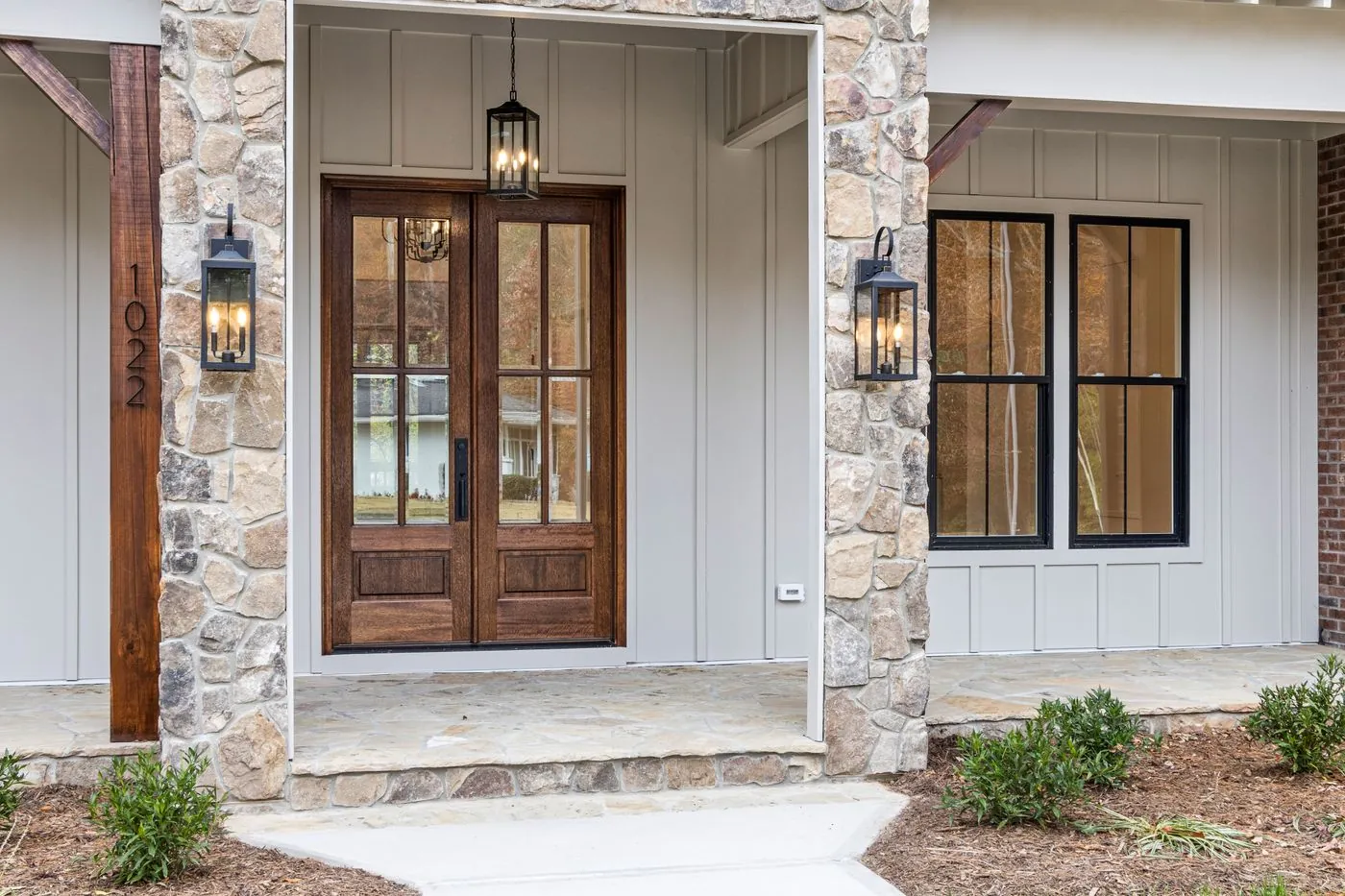 Finished house entrance with wooden double doors and black-framed windows. Photo by Curtis Adams on Pexels