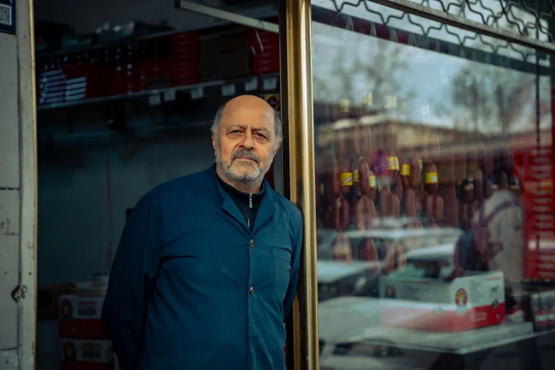 Shop owner standing in the doorway of a small food shop. Photo by Zeynep Sude Emek on Pexels