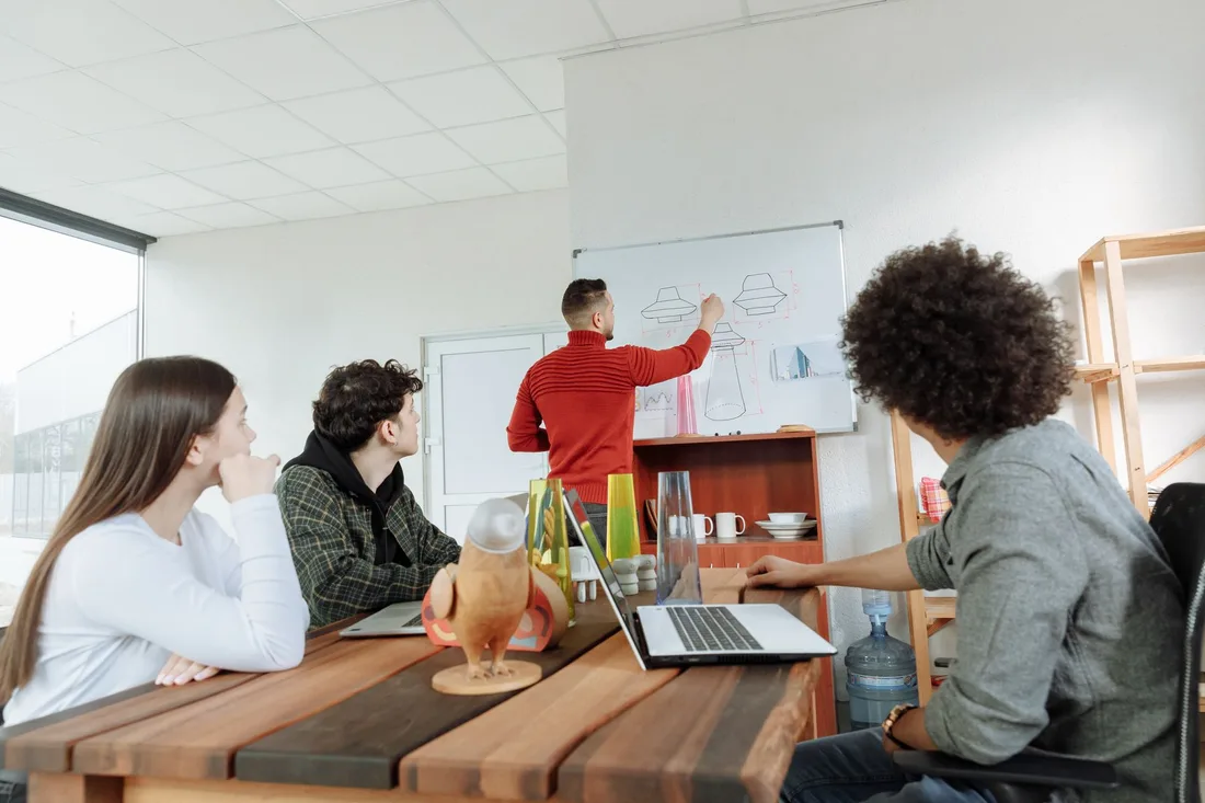 Startup founders meeting around a table with a whiteboard in a bright office in Singapore. Photo by Thirdman on Pexels