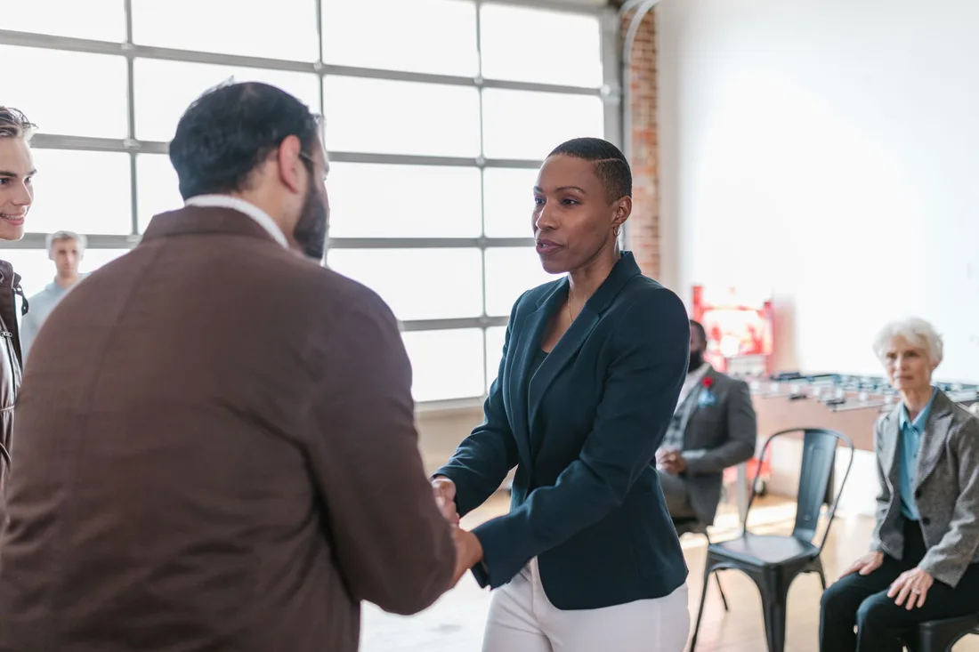 Business owners shaking hands in a bright office with colleagues behind in Singapore. Photo by RDNE Stock project on Pexels