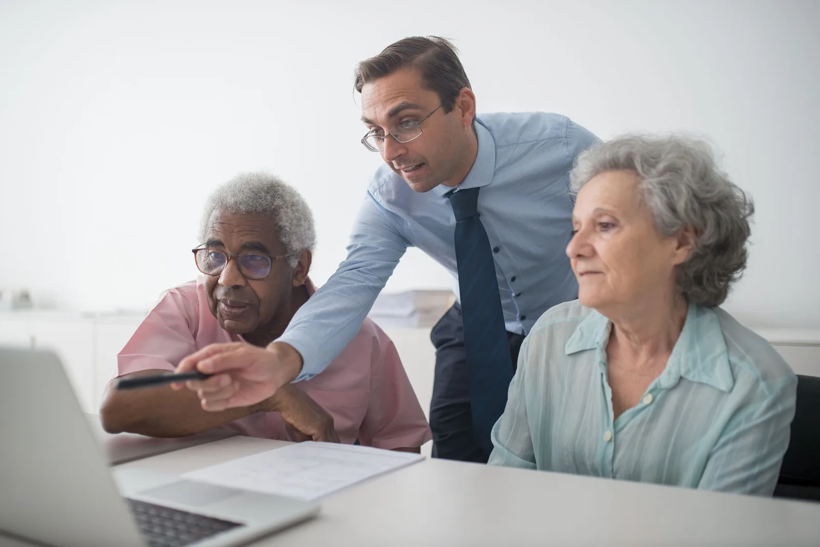 Financial advisor leaning in to explain a plan to an older couple at a table. Photo by Kampus Production on Pexels
