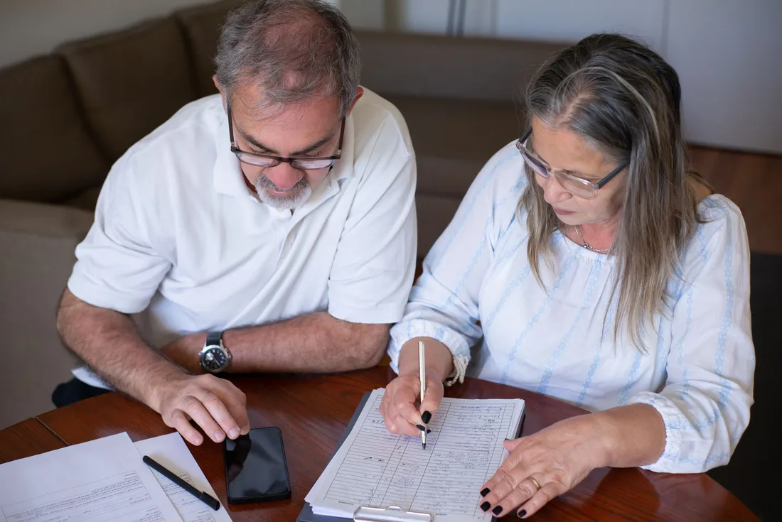 Retired couple filling out forms together at a table in Australia. Photo by Kampus Production on Pexels